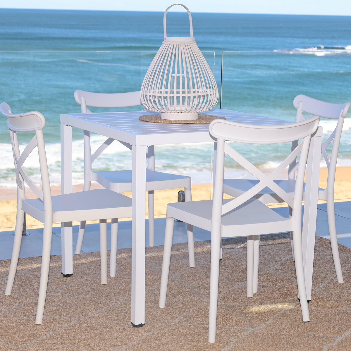 White dining table and chairs with a beach view