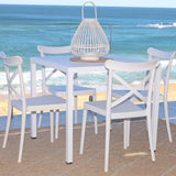 White dining table and chairs with a beach view