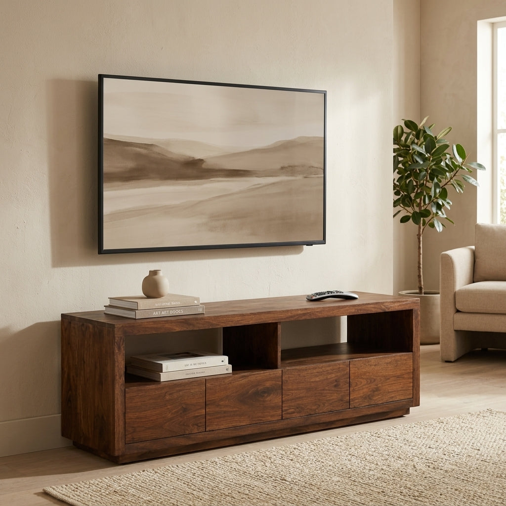 A dark brown wooden TV stand console in a modern living room setting, styled with books, a small vase, and a remote control, beneath a framed abstract landscape print.